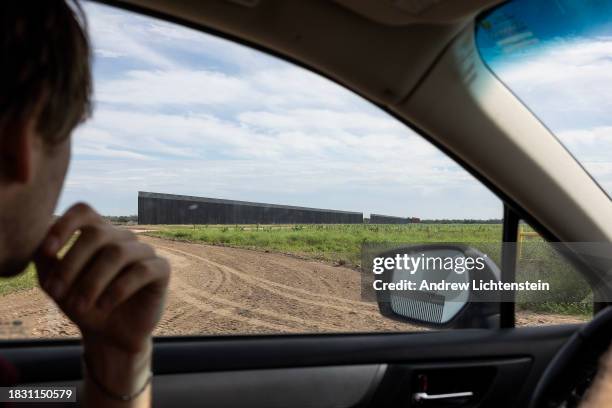 Driver passes unfinished sections of a border wall under construction that cuts through agricultural land about a mile inland from the Rio Grande...