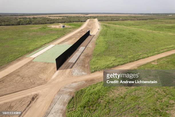 Aerial view, Unfinished sections of a border wall under construction cut through agricultural land about a mile inland from the Rio Grande River,...