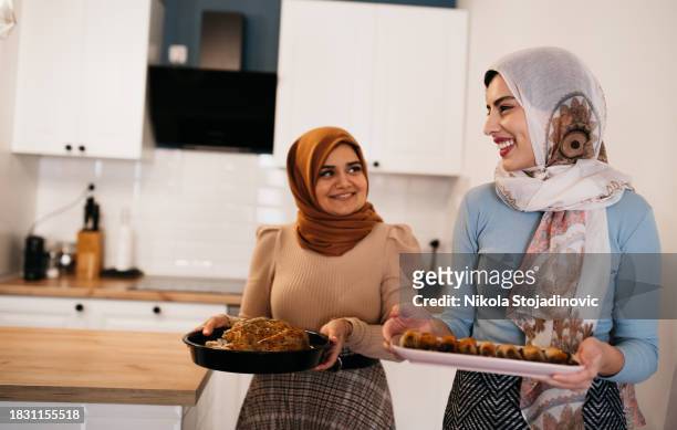 two muslim women serving dinner to their family - ramadan dinner stock pictures, royalty-free photos & images