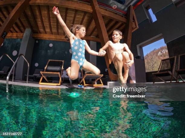 kids jumping in the pool - young girl jumping into swimming pool stock pictures, royalty-free photos & images