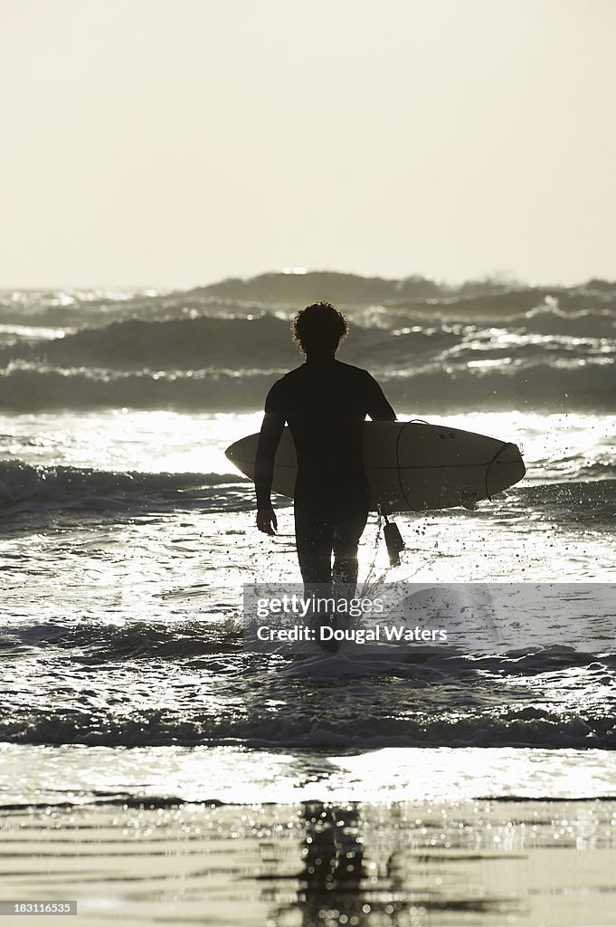 Surfer walking out to sea with surfboard