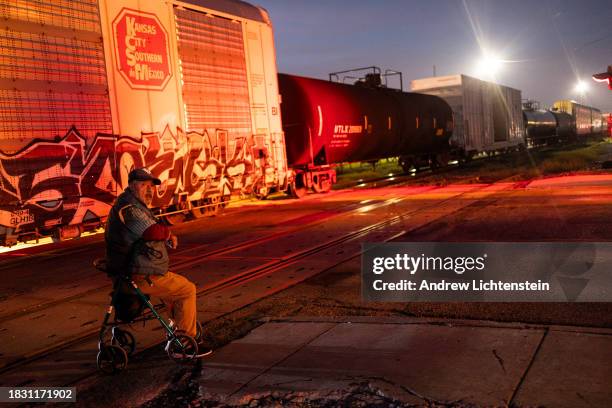 An elderly man waits for a freight train to pass before he can cross the street, November 30 in Eagle Pass, Texas.