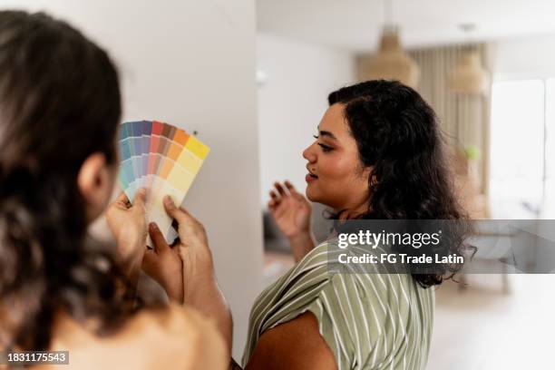 young woman talking with her husband to choose the color swatch of the wall at home - hand fan stock pictures, royalty-free photos & images