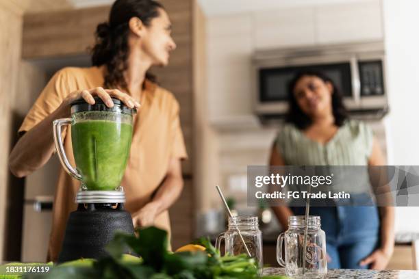 couple preparing detox juice in kitchen at home - detox stock pictures, royalty-free photos & images