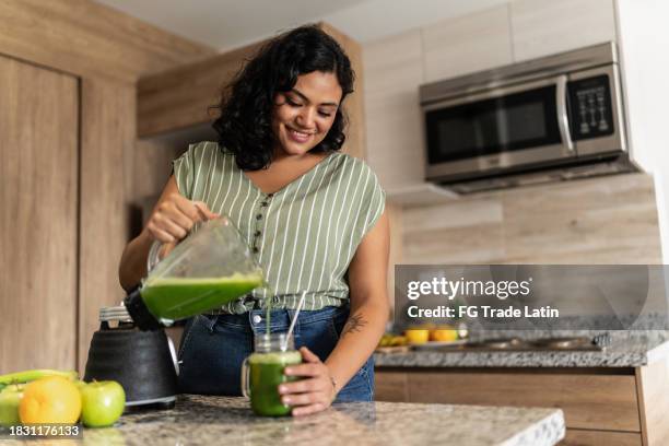 young woman preparing detox juice in kitchen at home - smoothie bildbanksfoton och bilder