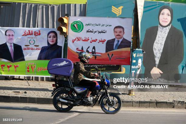 Man drives a motorcycle past electoral billboards in Baghdad on December 7 as Iraqis prepare to vote on December 18 to select councils in more than a...