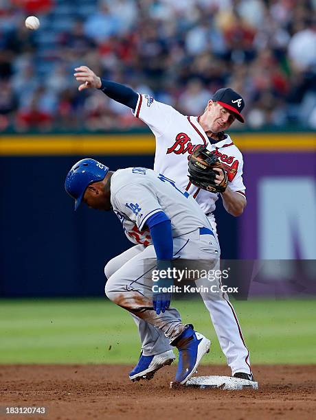 Elliot Johnson of the Atlanta Braves turns a double play as Carl Crawford of the Los Angeles Dodgers slides into second in the third inning during...