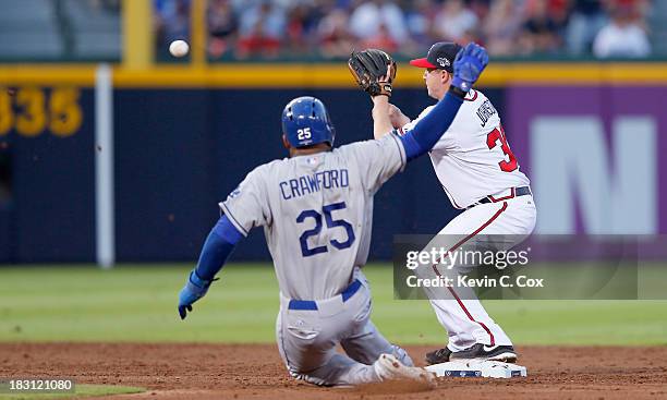 Elliot Johnson of the Atlanta Braves turns a double play as Carl Crawford of the Los Angeles Dodgers slides into second in the third inning during...