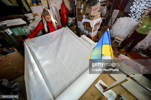 Valentyna Tyshkevych, a volunteer, is cutting white fabric into strips as the Palyanytsya Volunteer Center is making winter camouflage netting for...