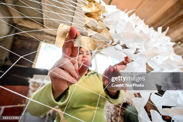 Volunteer is putting strips of white fabric onto netting as the Palyanytsya Volunteer Center makes winter camouflage netting for the Ukrainian...
