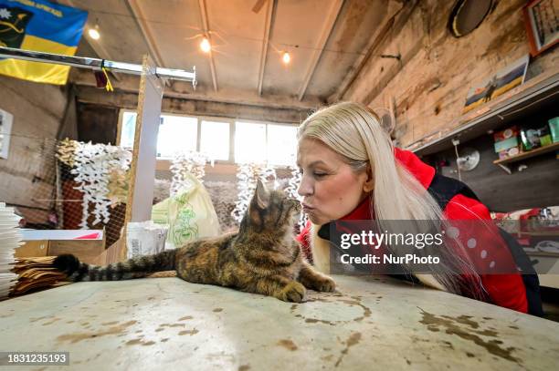 Valentyna Tyshkevych, a volunteer, is kissing a cat at the Palyanytsya Volunteer Center in Zaporizhzhia, southeastern Ukraine, on December 5 where...