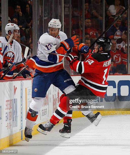 Adam Henrique of the New Jersey Devils bounces off Colin McDonald of the New York Islanders at the Prudential Center on October 4, 2013 in Newark,...