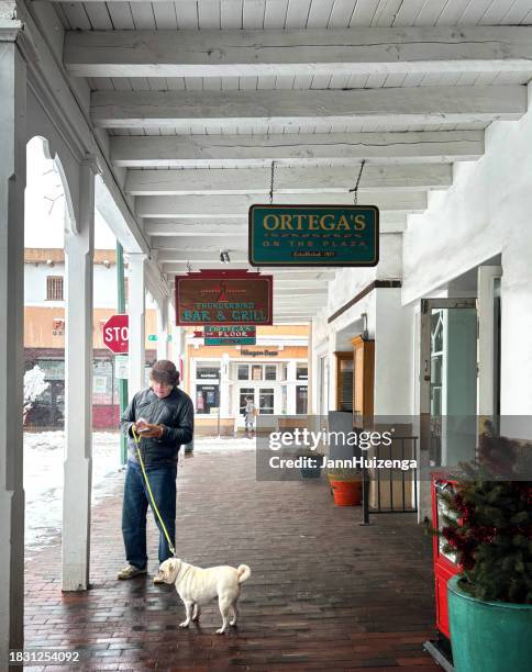 santa fe, nm: senior man with pug on snowy plaza - small town america stock pictures, royalty-free photos & images