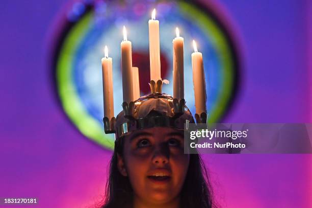 Worshipper is wearing a crown of candles to represent Saint Lucia as she leads a St. Lucia's Day celebration at the Evangelical Lutheran Church in...