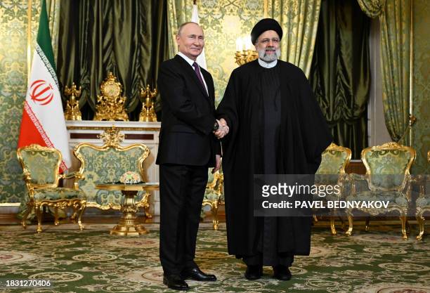 In this pool photograph distributed by Russian news agency Sputnik, Russia's President Vladimir Putin shakes hands with Iran's President Ebrahim...