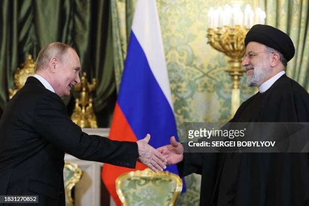 In this pool photograph distributed by Russian news agency Sputnik on December 7 Russia's President Vladimir Putin shakes hands with Iran's President...