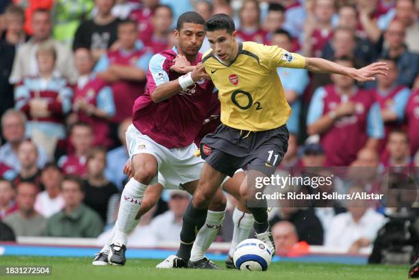 September 24: Robin Van Persie of Arsenal and Hayden Mullins of West Ham United challenge during the Premier League match between West Ham United and...