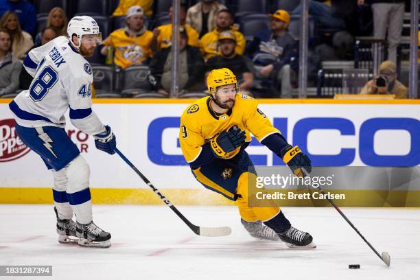 Filip Forsberg of the Nashville Predators reaches for the puck against Nick Perbix of the Tampa Bay Lightning during the first period at Bridgestone...