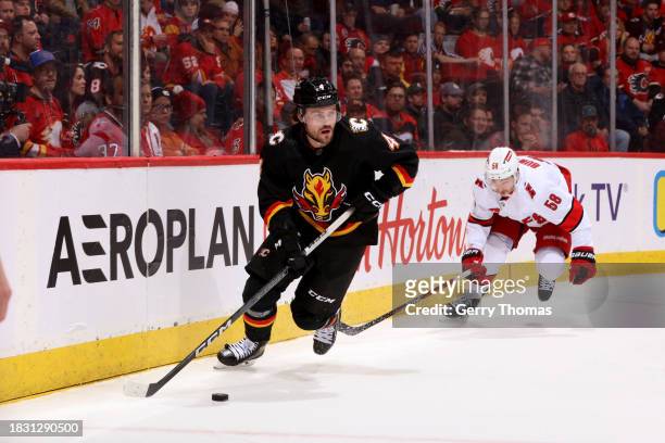 Rasmus Andersson of the Calgary Flames skates against Michael Bunting of the Carolina Hurricanes at Scotiabank Saddledome on December 7, 2023 in...
