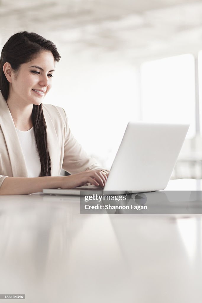 Smiling young businesswoman using her laptop