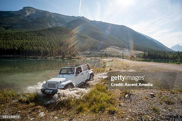 two women pilot jeep through lake shallows, mtns - jeep stock pictures, royalty-free photos & images