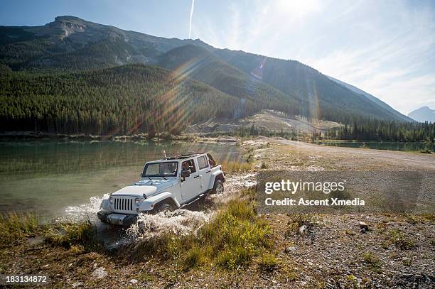 two women pilot jeep through lake shallows, mtns - 越野車 個照片及圖片檔