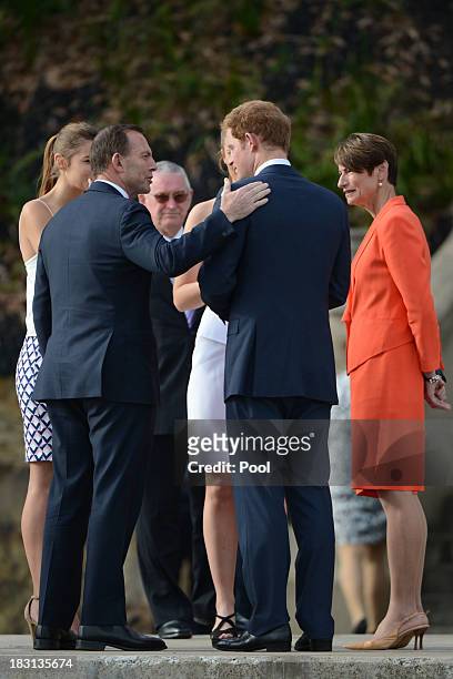 Prince Harry is greeted with a pat on the shoulder by Prime Minister Tony Abbott, his wife Margie and daughters Bridget and Frances after arriving at...