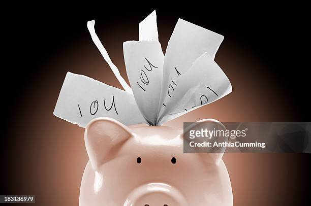 piggy bank stuffed full of iou notes on pink background - money borrow stockfoto's en -beelden