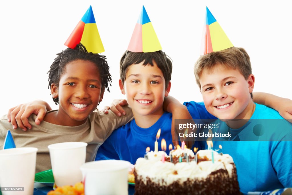 Three young boys celebrating birthday party with a cake
