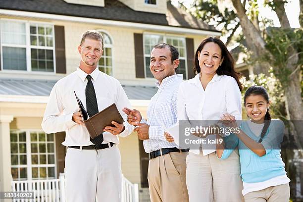 hispanic family with real estate agent in front of house - family of four in front of house stock pictures, royalty-free photos & images