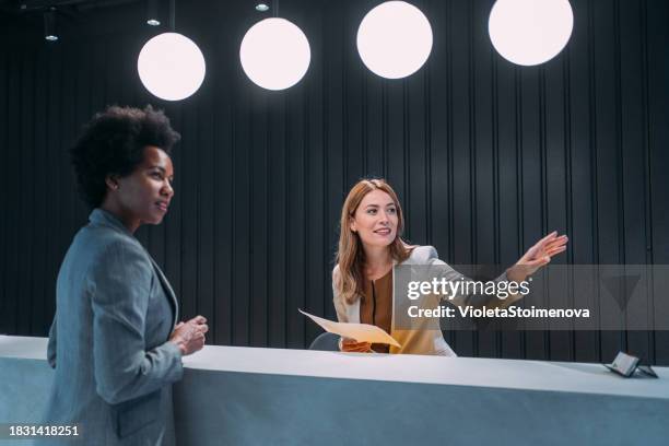 cheerful hotel receptionist assisting female guest. - hotelreceptie stockfoto's en -beelden