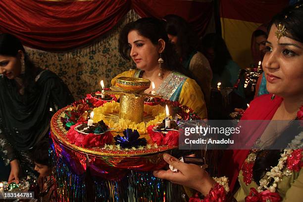 Groom's sisters bring traditional plate filled with henna and candles to stage during a henna ceremony on October 4, 2013 in Rawalpindi, Pakistan....