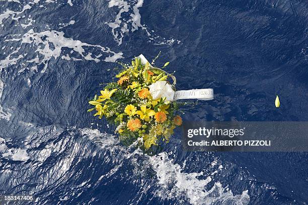 Picture taken on October 5, 2013 shows a bunch of flowers reading "Dead at sea" floating in the sea near the Lampedusa harbour after a boat with...