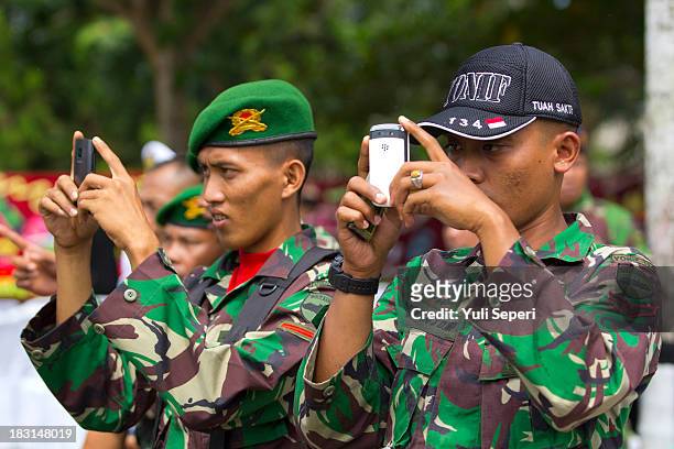 Indonesia army soldiers take pictures on their mobile phones during the 68th anniversary commemoration of the Indonesian Military or TNI on October...