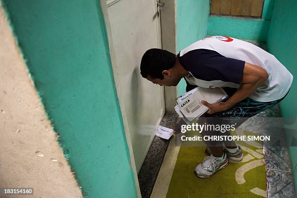 An employee of "Carteiro Amigo" --a local postal service-- delivers letters in Rocinha slum in Rio de Janeiro on October 4, 2013. AFP PHOTO /...