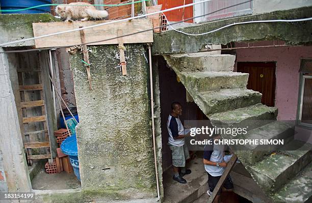 Employees of "Carteiro Amigo" --a local postal service-- deliver letters in Rocinha slum in Rio de Janeiro on October 4, 2013. AFP PHOTO / CHRISTOPHE...