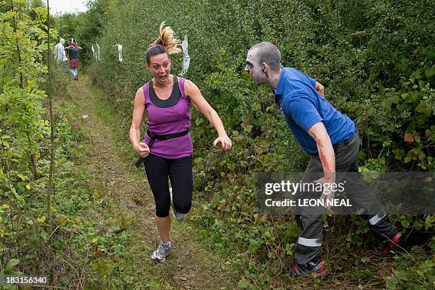 Volunteer "zombie" scares a participating runner during one of Britain's biggest horror events, the "Zombie Evacuation Race" at Carver Barracks near...