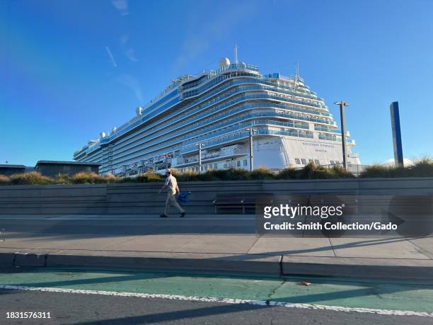Pedestrian walking along The Embarcadero with the Discovery Princess cruise ship docked in the background on a clear day, Port of San Francisco,...