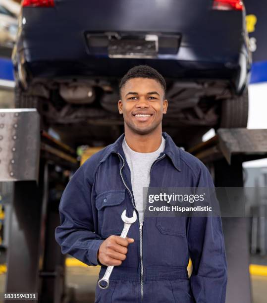 meccanico felice che lavora in un'officina di riparazione auto - salopette foto e immagini stock