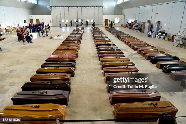 Coffins of some of the African migrants killed in a shipwreck off the Italian coast sit in a hangar at the Lampedusa airport on October 5, 2013 in...