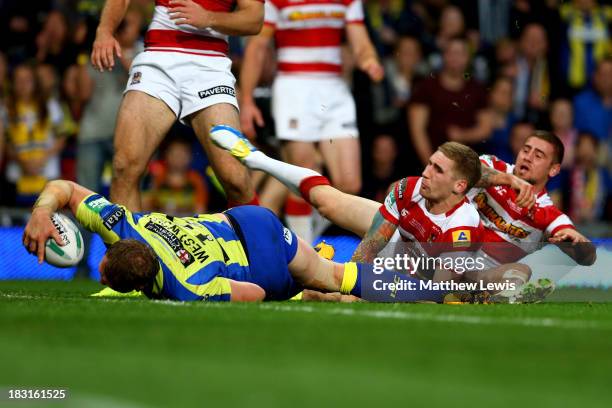 Ben Westwood of Warrington powers through the tackle from Sam Tomkins and Michael McIlorum of Wigan to score his team's third try during the Super...