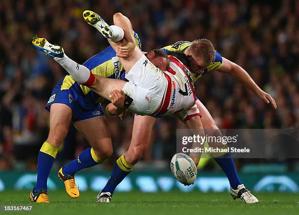 Matty Smith of Wigan Warriors is upended by Micky Higham and Mike Cooper of Warrington Wolves during the Super League Grand Final between Warrington...