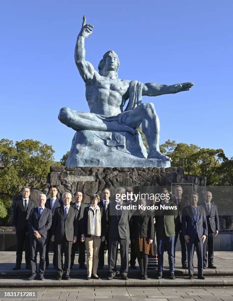 Attendees take part in a photo session in front of the Peace Statue at Peace Park in the atomic-bombed city of Nagasaki, southwestern Japan, on Dec....