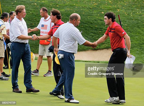 Phil Mickelson and Keegan Bradley of the U.S. Team shake hands on the 17th green after defeating Ernie Els and Brandon de Jonge of the International...