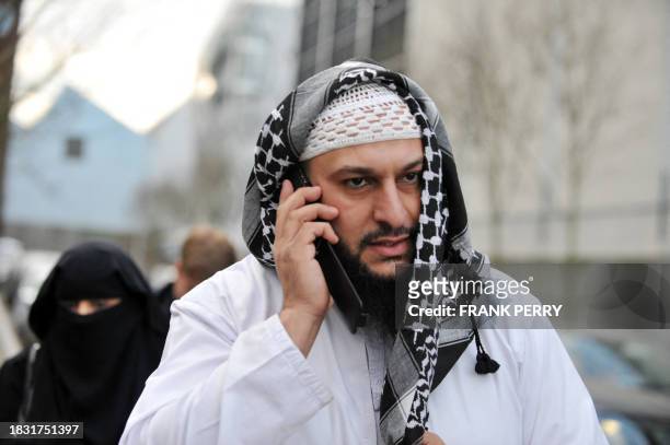 French owner of a chain of butcher's and grocery shops, Lies Hebbadj uses his mobile phone outside the court of justice where two of his "wives" were...