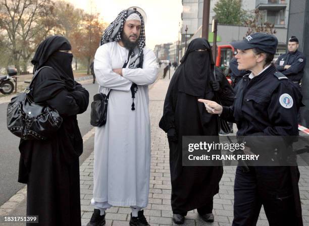 Police woman carries out an identity check of a "wife" wearing a full-face veil of French owner of a chain of butcher's and grocery shops, Lies...