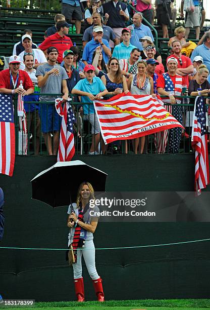 Captain Fred Couples' girlfriend Nadine Moze poses with fans on the first tee during Day Three Foursome Matches of The Presidents Cup at Muirfield...