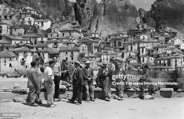 Workers waiting for employment, in the village of Castelmezzano , Italy, 1957. From the exhibition "Olives and bolts - farm laborers and factory...