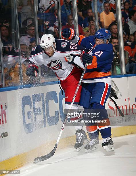 Kyle Okposo of the New York Islanders hits David Savard of the Columbus Blue Jackets into the boards at the Nassau Veterans Memorial Coliseum on...