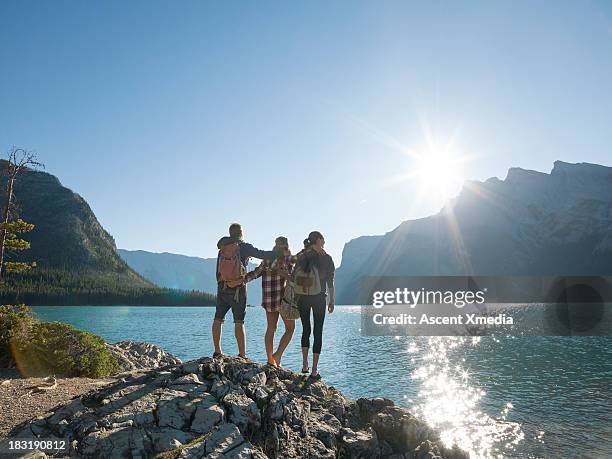 three friends embrace at edge of mountain lake - banff national park stock-fotos und bilder